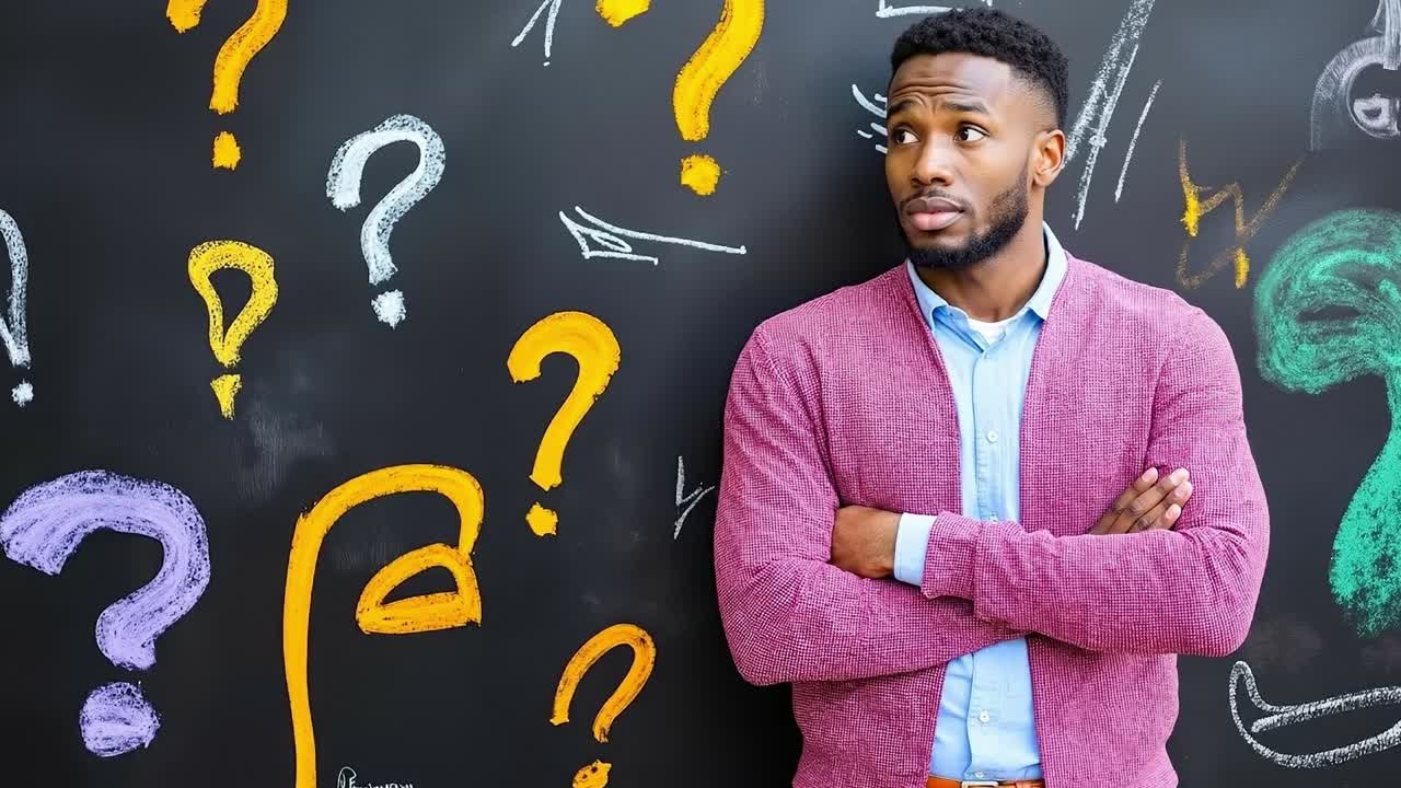 A man standing in front of a blackboard with question marks on it