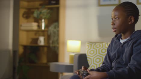 niño en casa sentado en un sofá con controlador jugando videojuegos