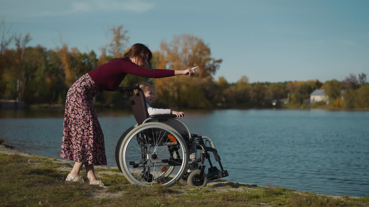 madre joven habla a sentado en silla de ruedas hija pequeña