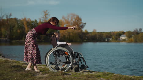 young mother speaks to sitting in wheelchair little daughter