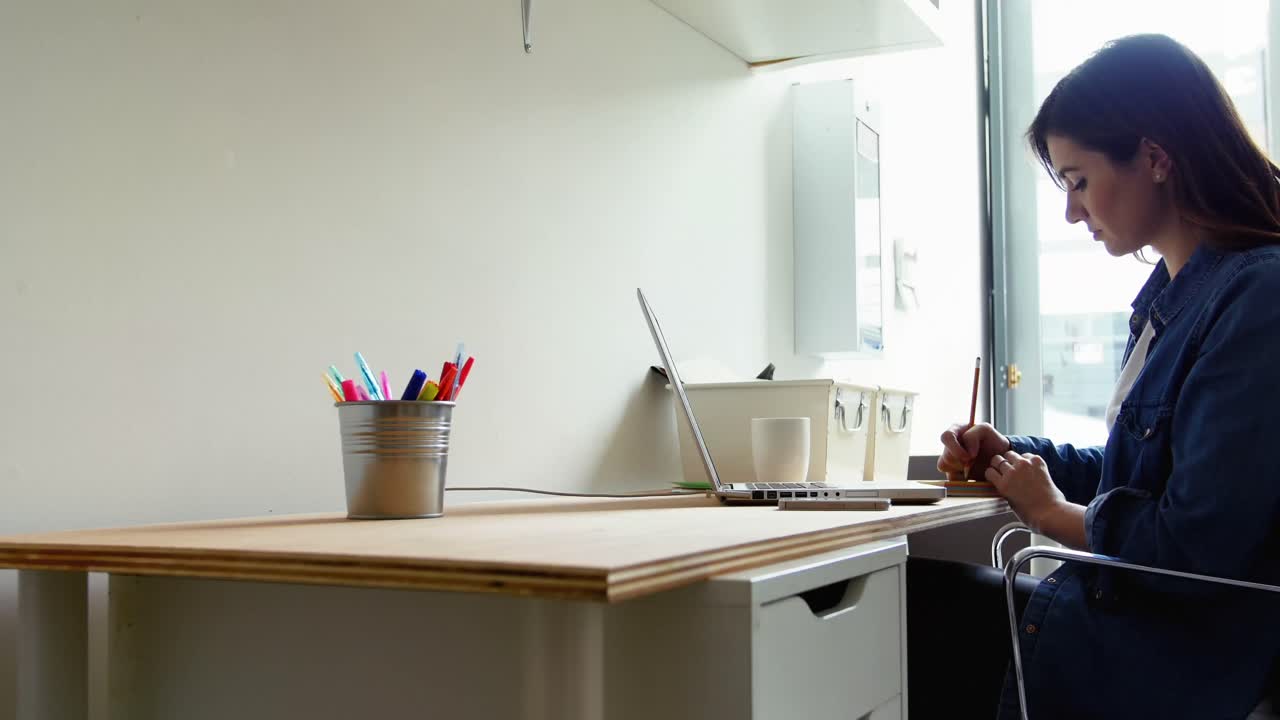 ejecutiva hablando por teléfono móvil mientras usa una computadora portátil