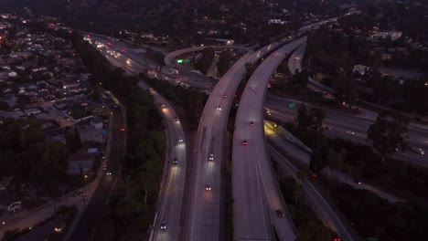 Aerial-view-cars-driving-on-freeway-at-interchange-in-evening-with-headlights
