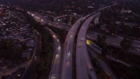 aerial view cars driving on freeway at interchange in evening with headlights