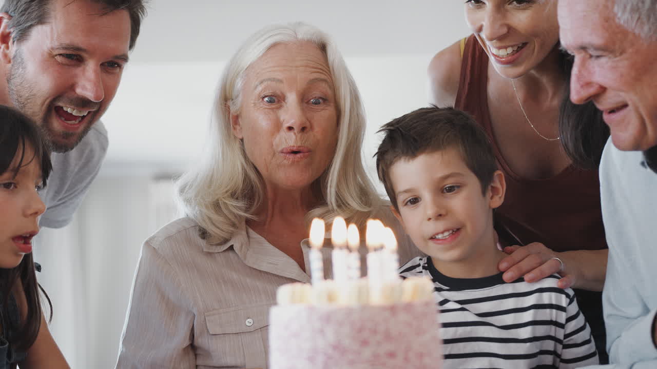 Famiglia multigenerazionale che festeggia il compleanno con la nonna a casa mentre spegne le candeline