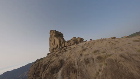 vista aérea de estilo libre fpv arriba y sobre roca roque nublo, cumbre de montaña extrema, gran canaria