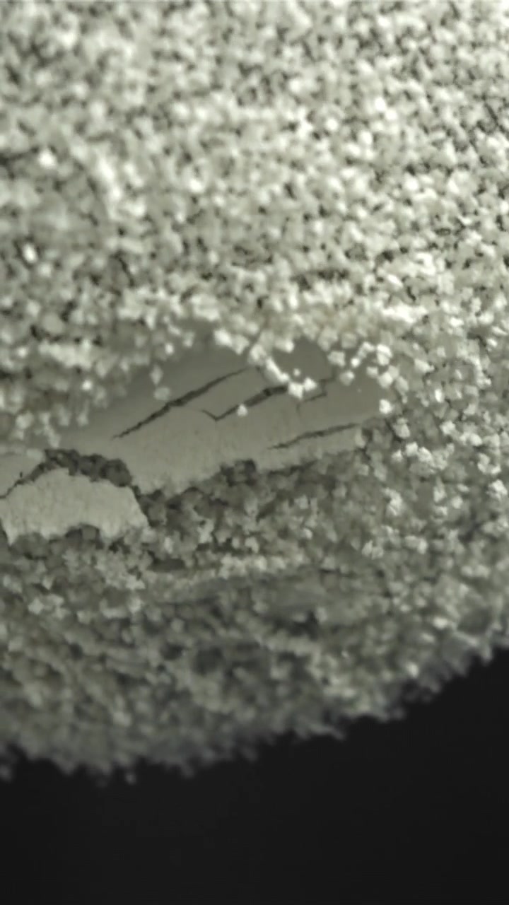 Toma macro de polvo granular blanco cayendo sobre una superficie texturizada gris
