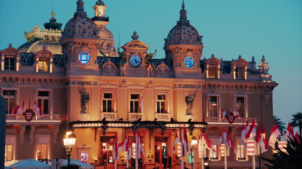 Monte Carlo, Monaco - October 24, 2024: The coat of arms of Monaco and multiple flags waving in front of the Monte Carlo Casino in the evening