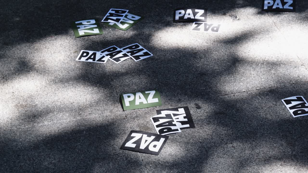 Person Walking Over Scattered 'Paz' Peace Cards on Concrete