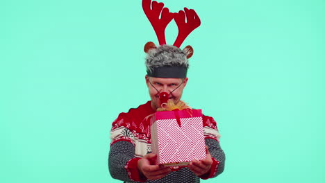 Funny-man-wears-red-New-Year-sweater-and-deer-antlers-presenting-Christmas-gift-box,-shopping-sale
