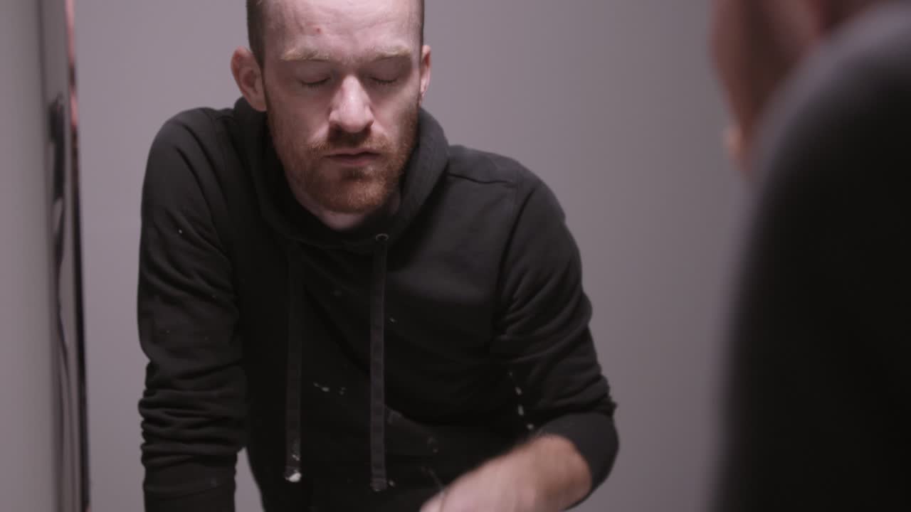 un hombre con una capucha negra salpicando agua en su cara y lavándola sobre su cabeza en el baño