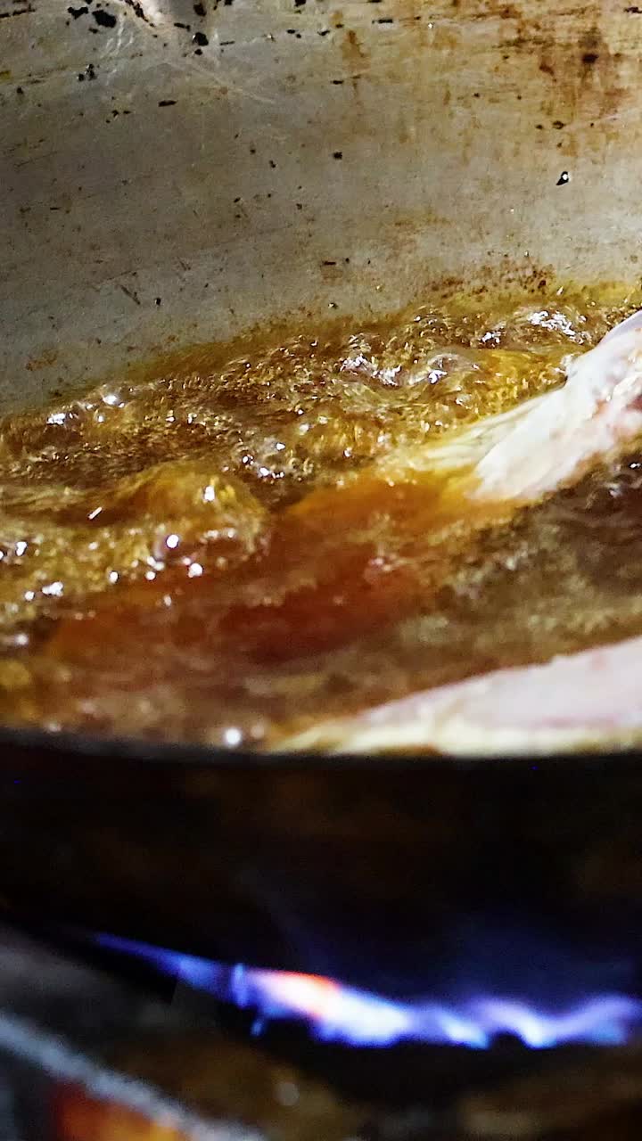 Pork chop frying in a pan over flames