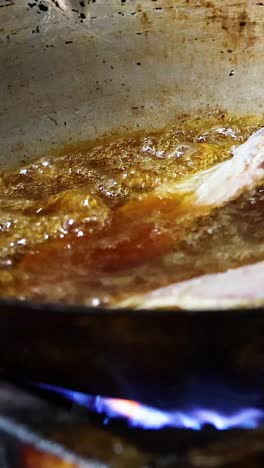 pork chop frying in a pan over flames