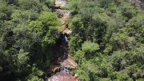 Aerial-orbits-to-reveal-small-rugged-waterfall-in-lush-forest,-Bolivia