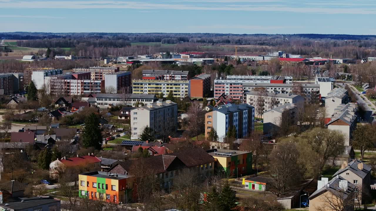 Colorful residential blocks in Kuldīga shine in crisp spring sun under blue sky
