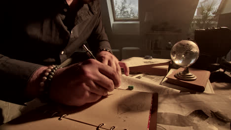 man writing in a study filled with vintage books and globe
