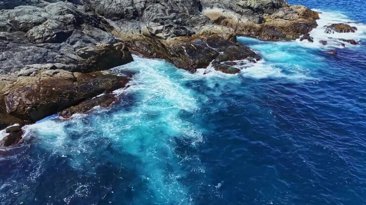 Costa con onde che si infrangono contro le rocce vicino all'oceano sotto la luce del sole in una regione costiera