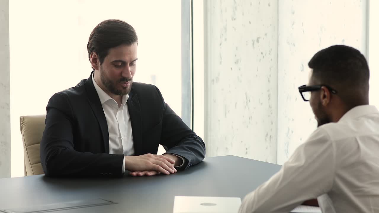 Applicant answers questions during job interview in company boardroom