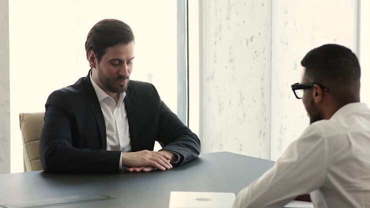 Applicant answers questions during job interview in company boardroom