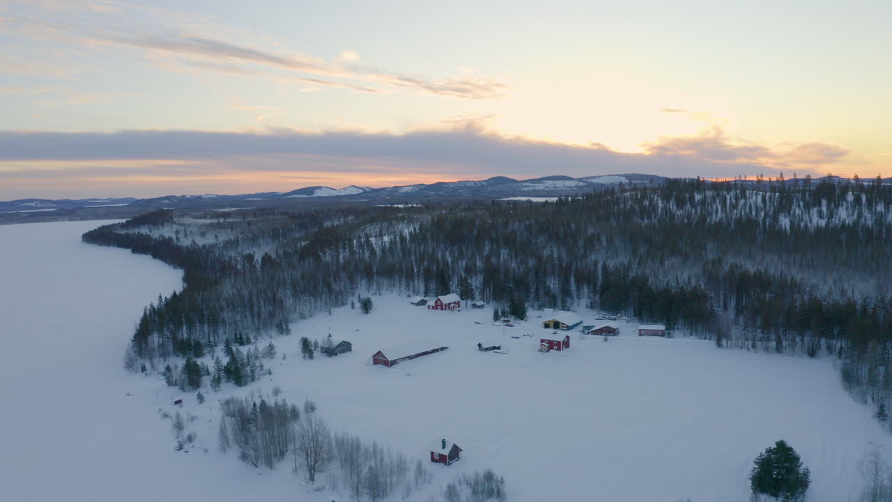 Aerial view quiet secluded wild rural snow covered cabins surrounded by Scandinavian woodland wilderness
