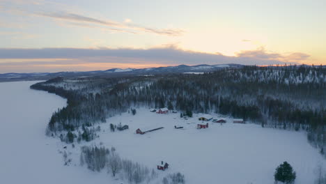 Vista-Aérea-Tranquilas-Y-Aisladas-Cabañas-Cubiertas-De-Nieve-Rural-Salvaje-Rodeadas-De-Bosque-Escandinavo-Desierto