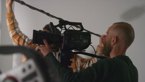 Male-Sound-Recordist-And-Camera-Operator-Working-On-Film-Set-Shooting-Movie-Or-Video-In-Studio-2