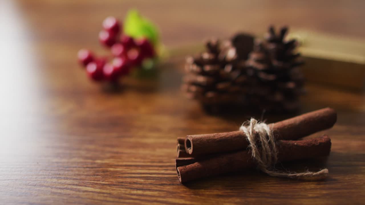 Vídeo de decorações de Natal com pinhas, canela e bagas vermelhas em fundo de madeira.