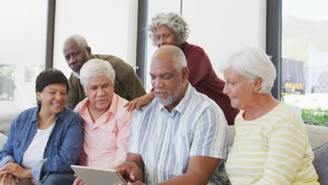 personas mayores felices y diversas hablando y usando tablets en el hogar de ancianos