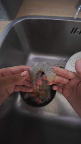 peeling shrimp in a kitchen sink