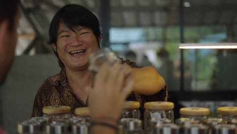 vendor interacts with a customer over glass jars of merchandise