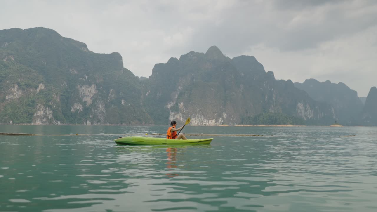 Person Kayaking on a Scenic Lake with Limestone Mountains