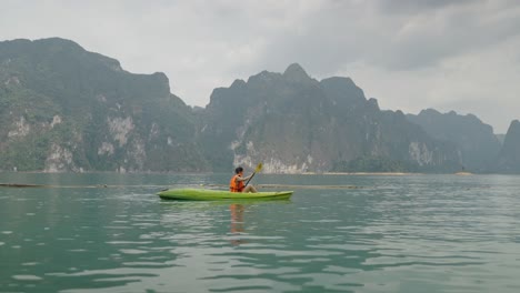 person kayaking on a scenic lake with limestone mountains