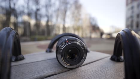 close-up of a camera lens on a wooden bench in a park