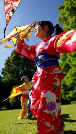 children in kimonos flying kites in a park