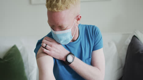 happy albino african american man wearing face mask, with a plaster after vaccination