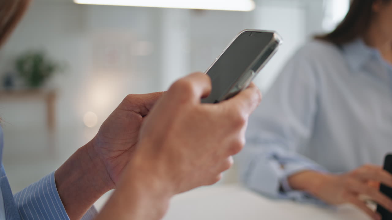 여성의 손이 작업장에서 화면을 스크롤합니다. 사무실 관리자가 휴대전화를 스와이프합니다.