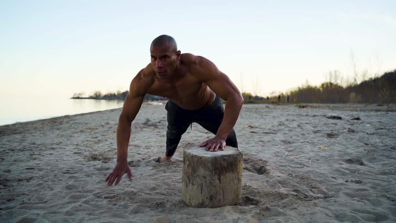 atleta musculoso haciendo flexiones en una playa en cámara lenta