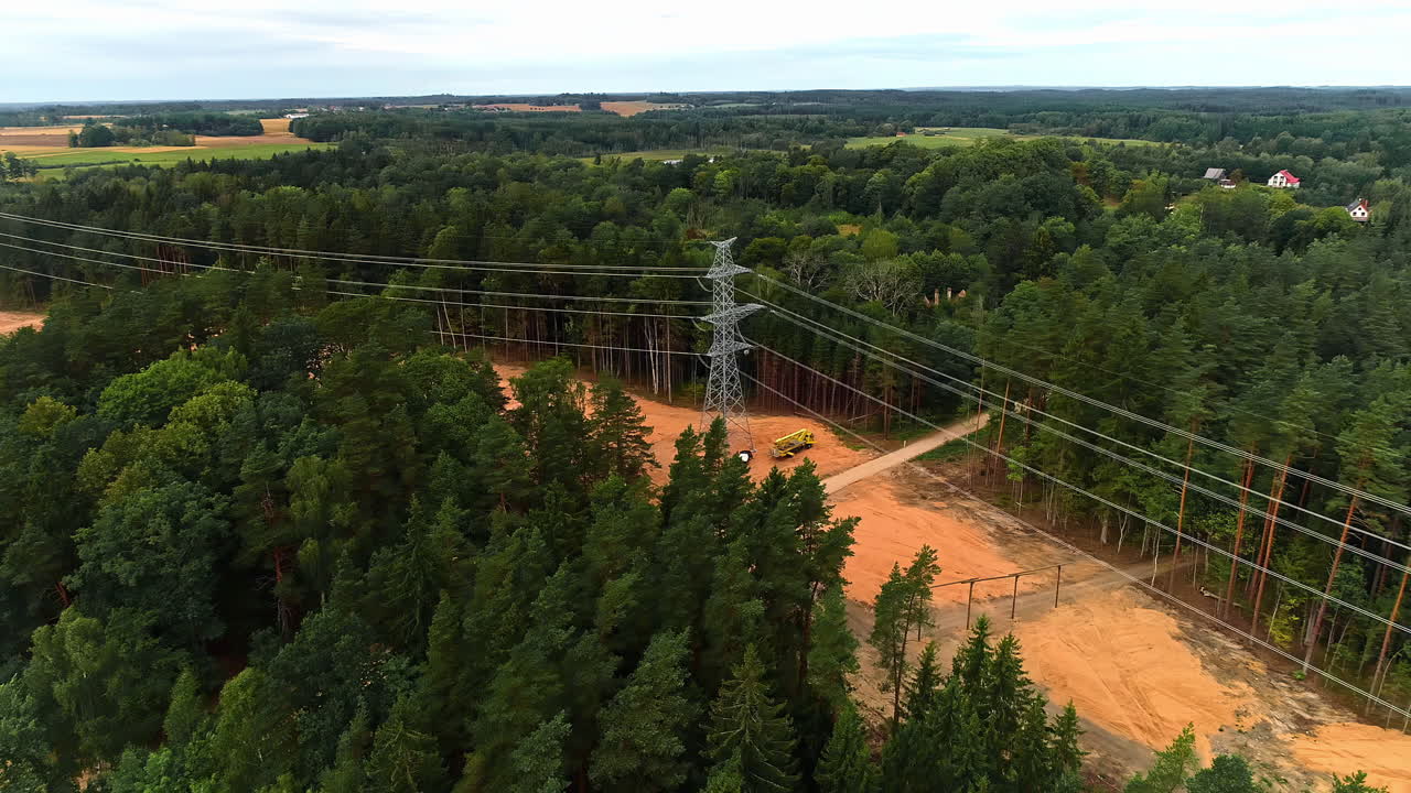 vuelo aéreo de drones sobre un bosque con un sitio de construcción que muestra a un trabajador instalando nuevas torres de transmisión