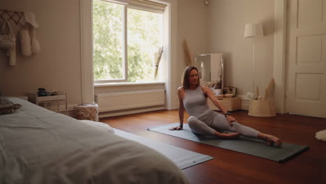 woman stretching on a yoga mat in a bedroom