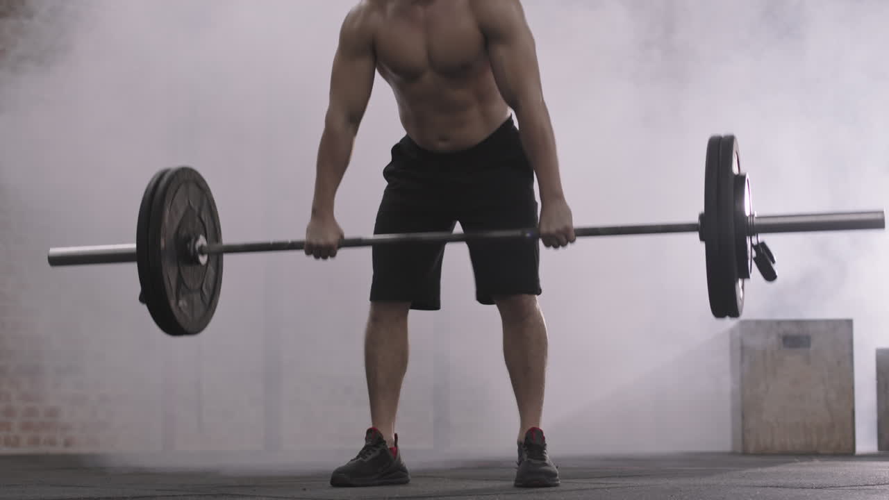 Young Sportsman Lifting Barbell during Training