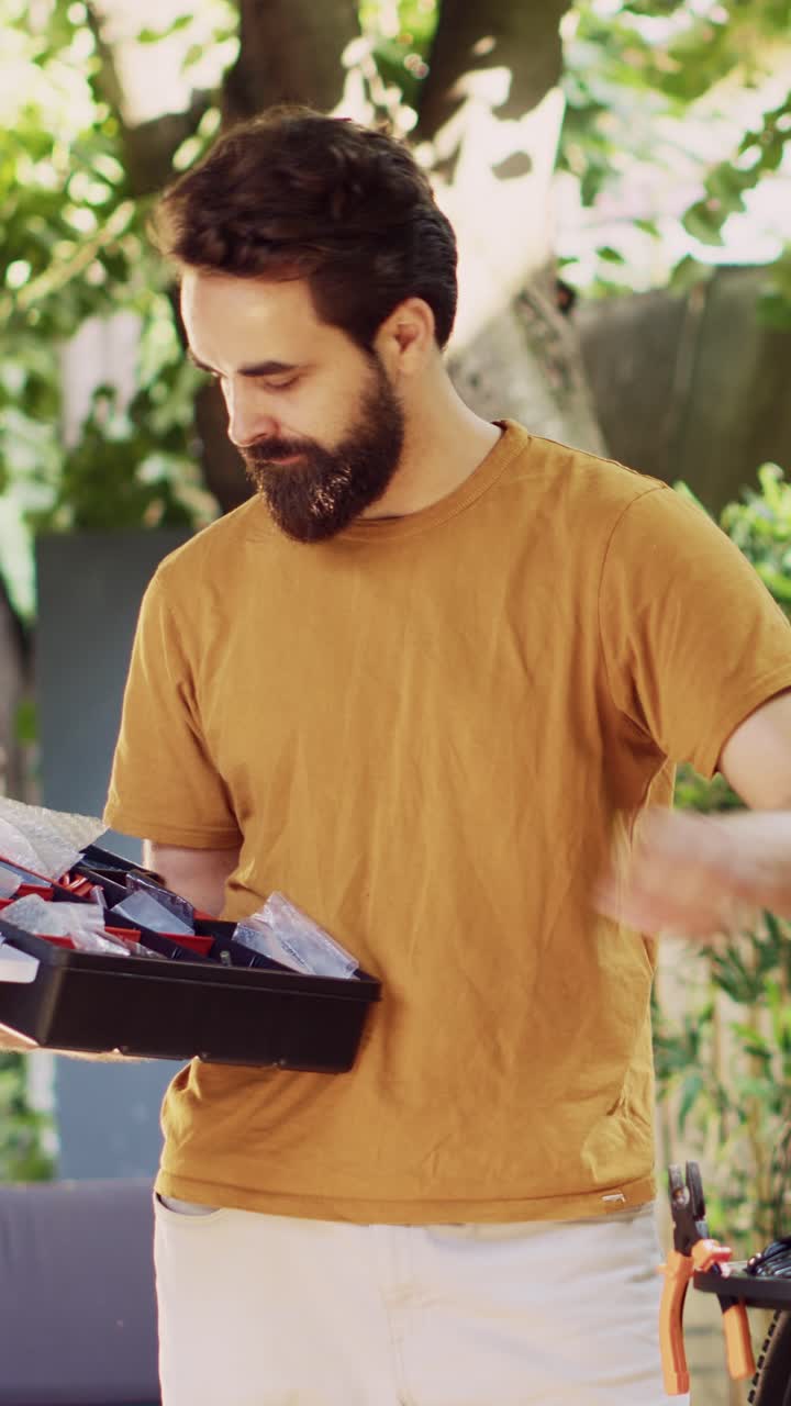 Man with beard holding toolbox in garden