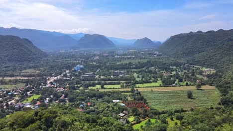 aerial 4k drone footage flying into a valley with a small countryside town between mountain ranges in khao yai, thailand