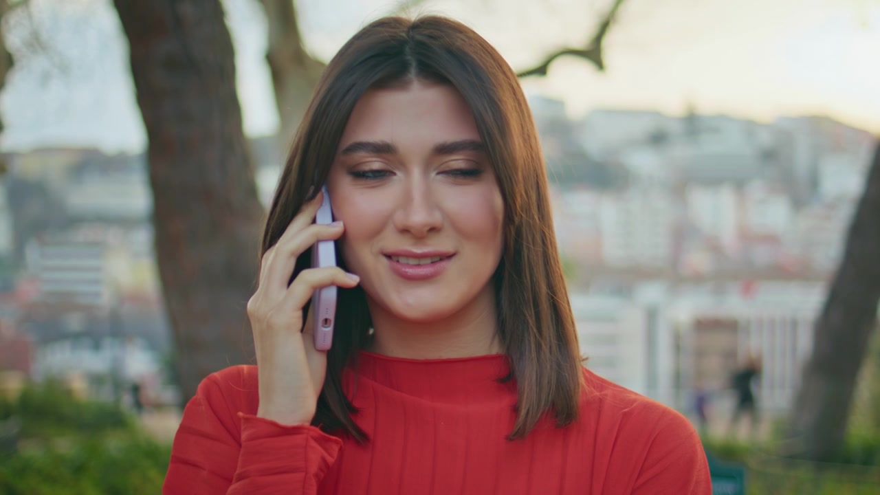 Mujer en primer plano hablando por teléfono móvil en el parque. Chica contestando una llamada en un mirador al atardecer.