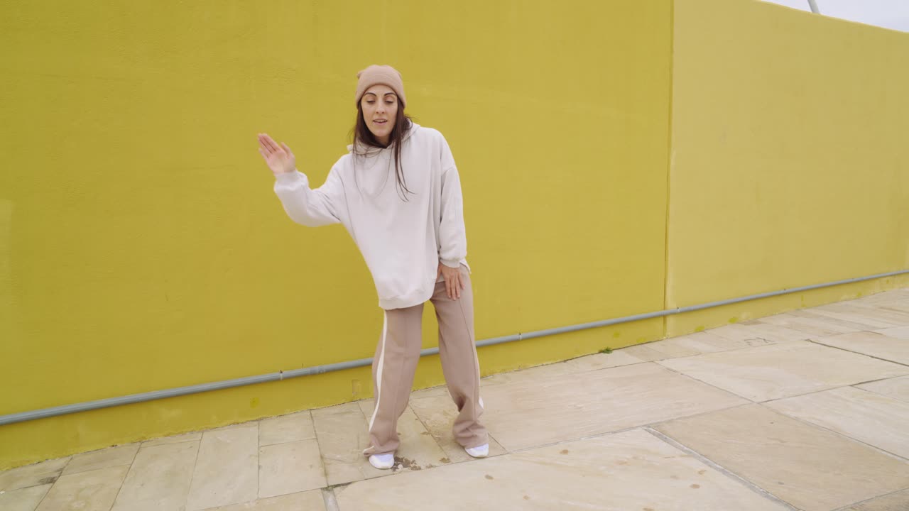 Woman in Beige Tracksuit Dancing on Street
