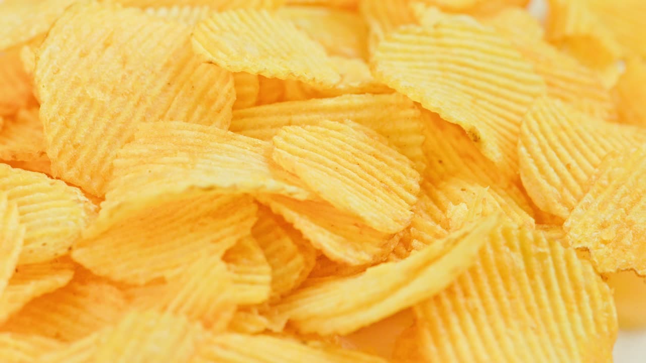 schegge di patate gialle ondulate rotanti a fotogramma completo sullo sfondo in primo piano
