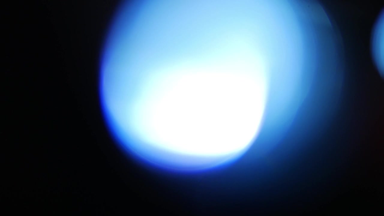 Fughe di luce blu dinamiche e bagliori dell'obiettivo su sfondo nero