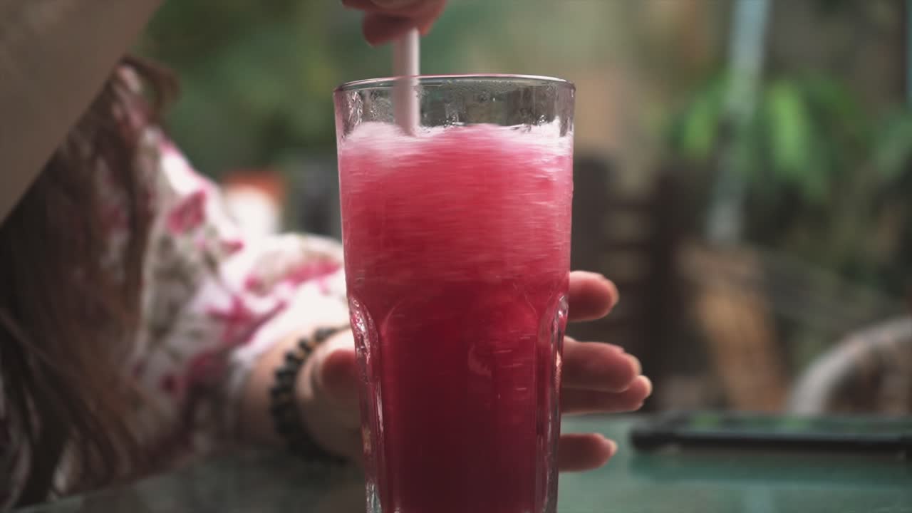 Forfriskende hvirvel: Nærbillede af en rød slushice-drink, der blandes i et glas
