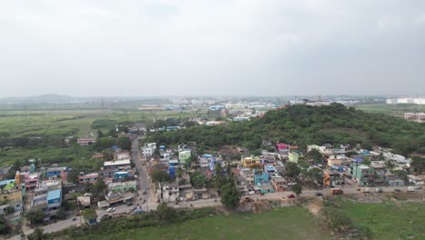 Toma-Aérea-De-Una-Colina-Rodeada-De-Pequeñas-Casas-En-La-Ciudad-India