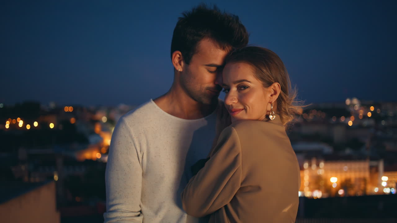 Romance girl cuddling guy looking camera at night city closeup. Tender couple