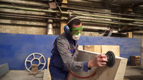 worker sanding wood panel in a factory setting