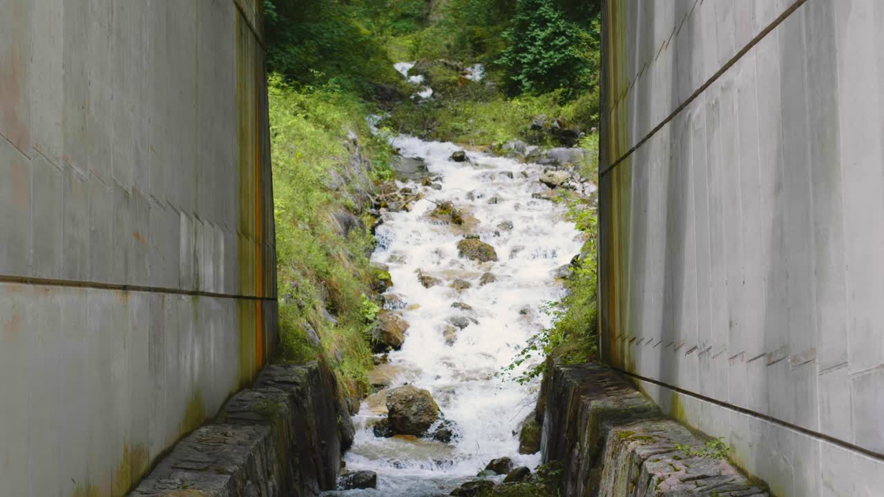 주변에 콘크리트 댐 구조가 있는 숲을 흐르는 돌이 있는 작은 개울의 경치 좋은 샷